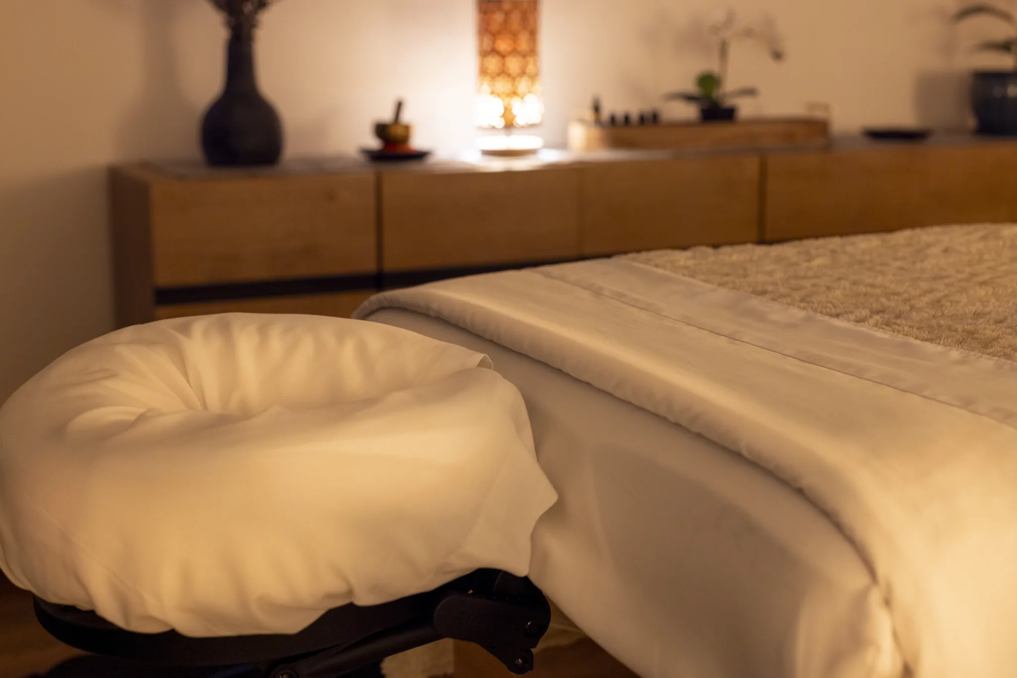 A prepared massage table and face cradle in the warmly lit treatment room.
